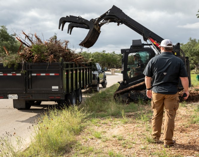 Worker standing in front of skid steer