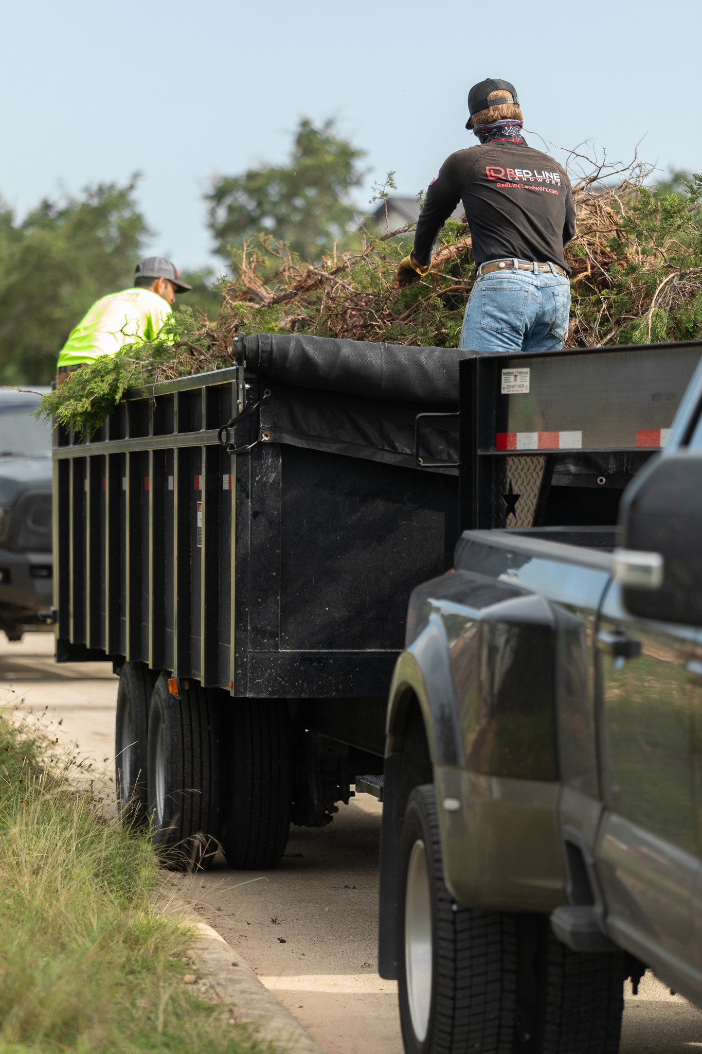 workers cutting brush in in trailer with truck